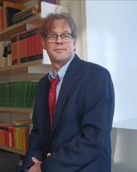 man in suit sitting on desk in front of books